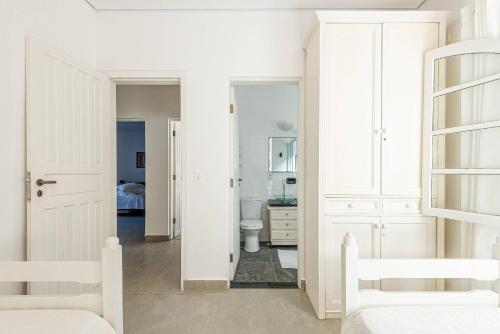 a white bathroom with a toilet and a sink at 4 dorm com piscina a 350 m de Camburizinho in Camburi