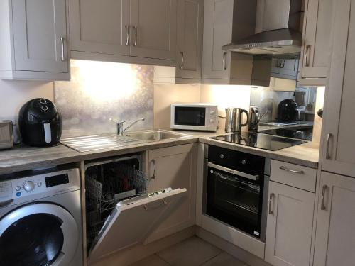 a kitchen with a washer and a sink and a dishwasher at Promenade Cottage, Newcastle, County Down in Widows Row