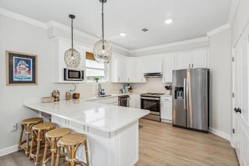 a kitchen with white cabinets and a large island with bar stools at Blue Horizon at Pensacola Beach - Heated Pool, Across beach access, Beach gear, Dogs OK! in Pensacola Beach