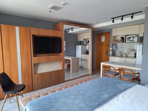 a bedroom with a bed and a tv and a kitchen at JADE - Flat Particular in Brasilia