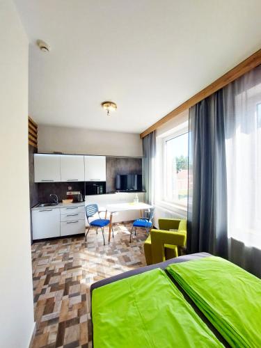 a bedroom with a green bed and a kitchen at Wesendorf Residenz Premium Lounge in Wesendorf