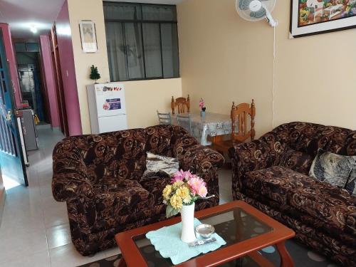 a living room with two couches and a table with flowers at Departamento 2 camas in Moyobamba