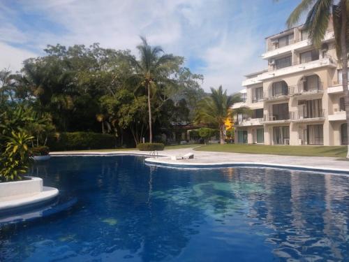 a large swimming pool in front of a building at Habitaciones con baño privado en Departamento compartido en Club Santiago Manzanillo in Manzanillo