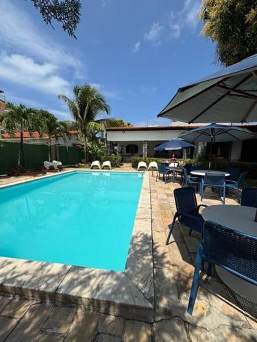 a swimming pool with a table and chairs and an umbrella at Ampla casa de 3 quartos com piscina em Serrambi PE a 50mts do mar in Porto De Galinhas