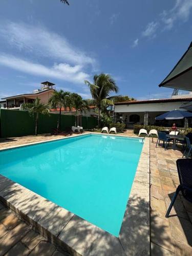 a large blue swimming pool with chairs and umbrellas at Ampla casa de 3 quartos com piscina em Serrambi PE a 50mts do mar in Porto De Galinhas