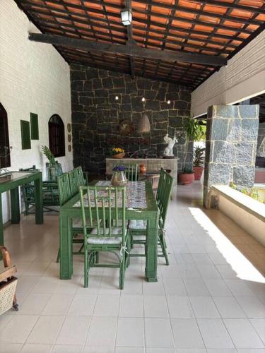 a green table and chairs on a patio at Ampla casa de 3 quartos com piscina em Serrambi PE a 50mts do mar in Porto De Galinhas