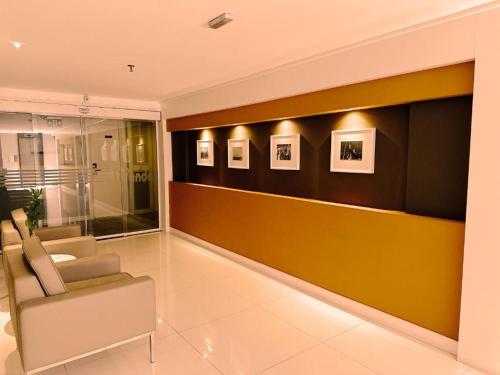 a living room with a chair and pictures on the wall at Kubitschek Plaza Hotel - Flat Particular 4 - ALM Hospedagens in Brasília