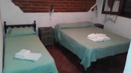 two beds in a room with green sheets and towels at El Castillito de Juan in Mina Clavero