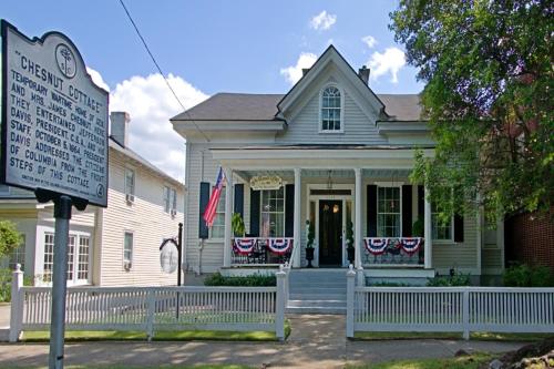 a white house with american flags on the porch at Chesnut Cottage Inn in Columbia