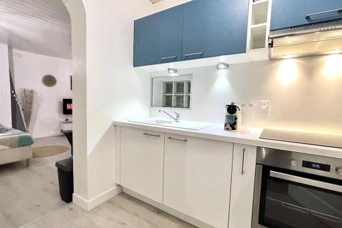 - une cuisine blanche avec des placards bleus et un évier dans l'établissement La Petite Fleur - Centre ville, à Niort