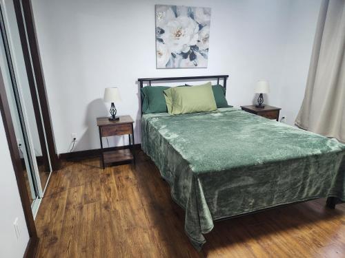 una camera da letto con un letto con lenzuola verdi e due tavoli di CASA VERONICA, 4 seasons Cottage a Gaspé