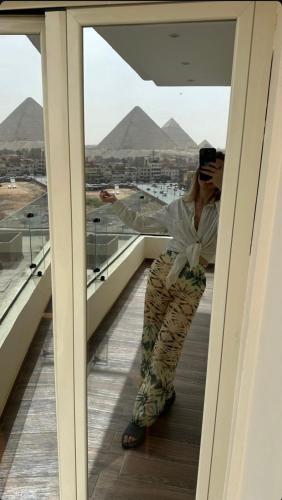 a man sitting on a balcony looking at the pyramids at Rotana Pyramids View in Cairo