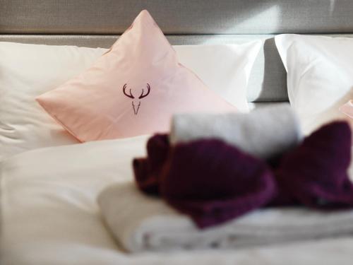 a bed with towels and a pillow with a deer on it at Zum Hirschen - hotel & gasthaus beim stöckeler in Scheidegg
