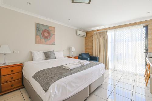 エメラルドにあるEmerald Central Palms Motelの大きな白いベッドと椅子のある寝室