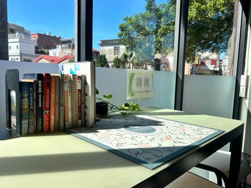 a table with books on it next to a window at 玩轉金門民宿2館-樂遊小鎮民宿 in Jincheng