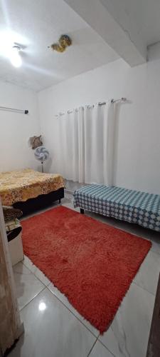 a room with two beds and a red rug at Kitnet para Férias in Massaguassu
