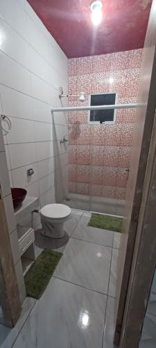 a bathroom with a toilet and a glass shower at Kitnet para Férias in Massaguassu
