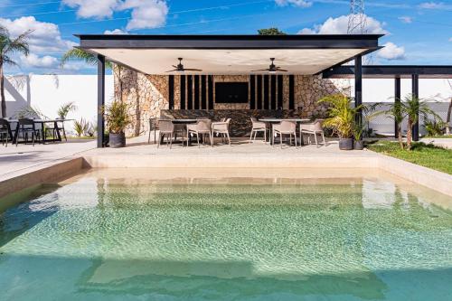 a swimming pool with a table and chairs next to a house at Departamento en Mérida en Privada con Amenidades in Xcanatún