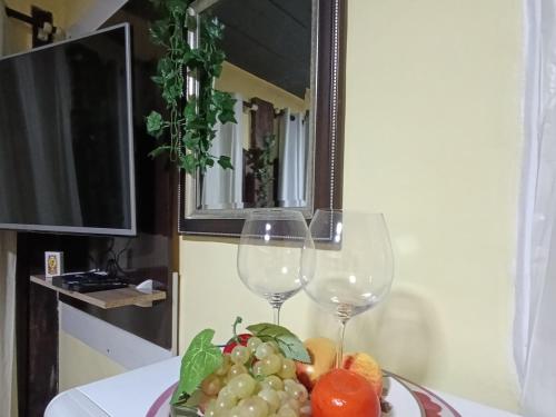 a plate of fruit and two wine glasses on a table at Residencial María in Bombinhas