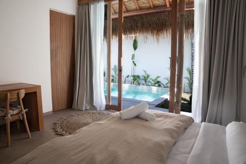 a bedroom with a bed with a view of a pool at Flora Villa Priv Pool By Yemaya in Kuta Lombok