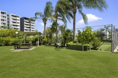 a park with a picnic table and palm trees at Duporth - Luxury Riverfront Apartment in Maroochydore