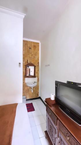 a bedroom with a bed and a tv and a bathroom at Rinjani Homestay in Pangandaran