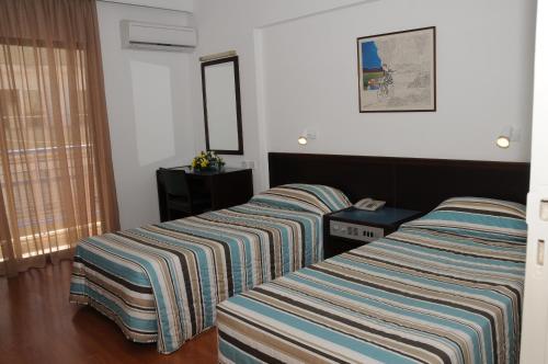 a hotel room with two beds and a mirror at Atrium Zenon Hotel Apartments in Larnaka