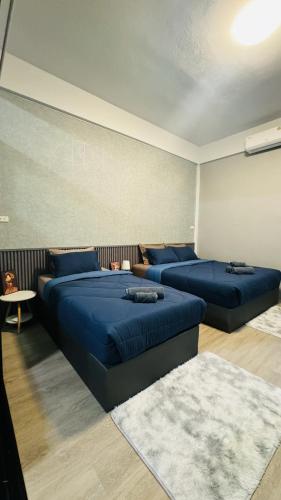 two beds in a room with blue pillows at K Siri House Hatyai in Hat Yai