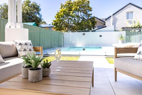 a patio with a wooden table and a pool at Welcome to Sandy Bottoms in Shoalhaven Heads