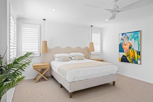a white bedroom with a bed and a painting on the wall at Welcome to Sandy Bottoms! in Shoalhaven Heads