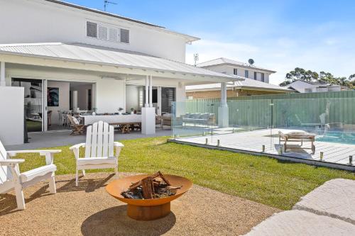 a backyard with chairs and a table and a house at Welcome to Sandy Bottoms in Shoalhaven Heads