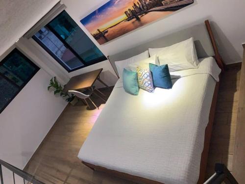 a bedroom with a white bed with four pillows at Casa Carolina Loft Aryaz in Tepoztlán