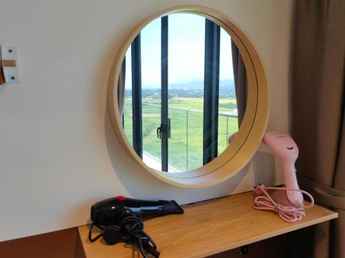 a round mirror sitting on a wooden shelf with a hair dryer at Near Airport K Avenue Family Room in Donggongon