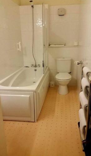 a bathroom with a white tub and a toilet at The Royal Hotel Tain in Tain