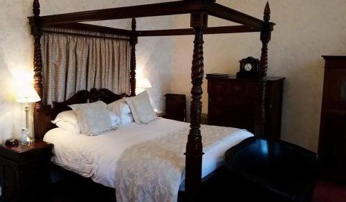 a bedroom with a large bed with a wooden canopy at The Royal Hotel Tain in Tain
