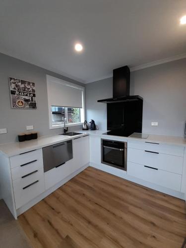 a kitchen with white cabinets and a wooden floor at Unit 46a in Timaru