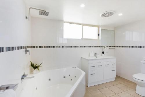 a white bathroom with a tub and a toilet at Baywatch 3 in Merimbula