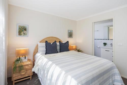 a bedroom with a large bed with blue pillows at Baywatch 3 in Merimbula