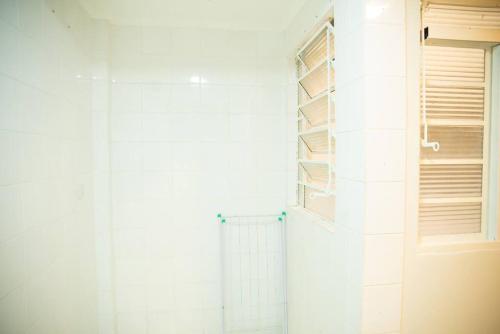 a white bathroom with a shower and a door at Excelente Apartamento em Presidente Prudente-SP in Presidente Prudente