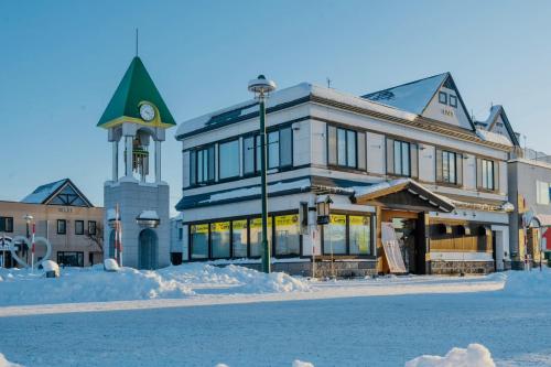 a large building with a clock tower on a street at ヴァンテアン舎（vingt et un house） in Biei