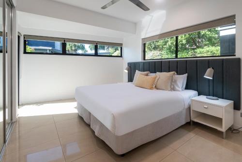 a bedroom with a white bed and two windows at Edge Apartments on Hamilton Island by HIHA in Hamilton Island