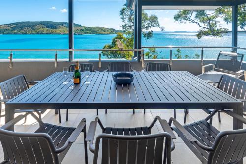 a blue table with chairs and a bottle of wine at Edge Apartments on Hamilton Island by HIHA in Hamilton Island
