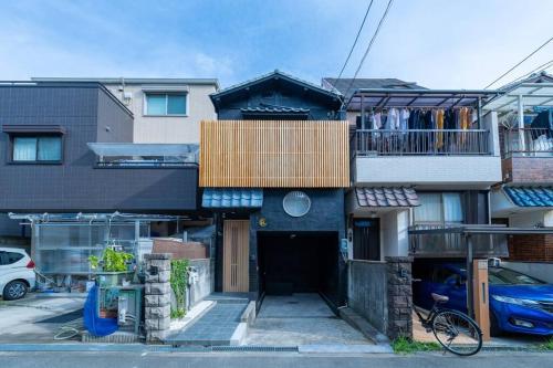 a building with a porch and a balcony with a house at Yume usjまで電車で1分 駐車場付きの日本の宿 寝室4つ お風呂 トイレ2つ 最大10名 in Osaka