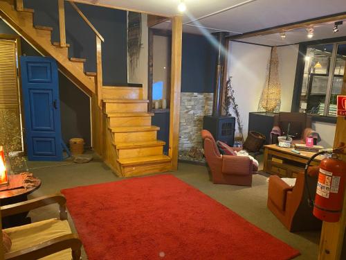 a living room with a staircase and a red rug at Hostal Amerindia in Puerto Natales