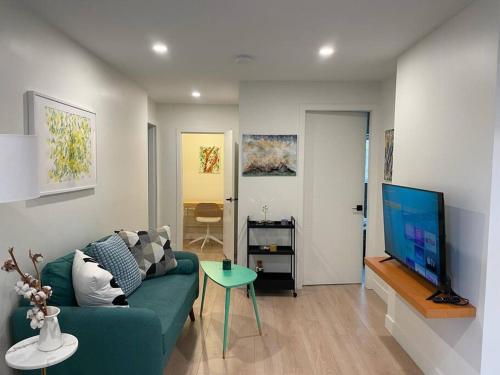 a living room with a blue couch and a flat screen tv at Almost Home in West Vancouver
