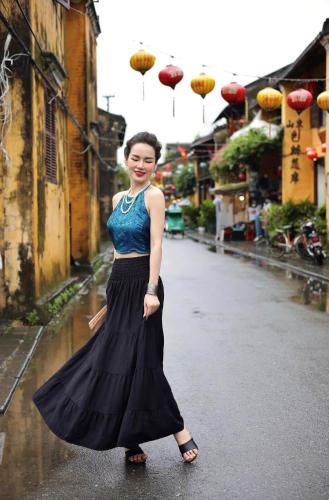 a woman is standing in a street with umbrellas at LA GAI HOMESTAY HOI AN in Hoi An
