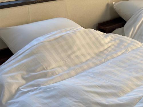 an unmade bed with a striped blanket and pillows at 最大5名様利用可 モダンでスタイリッシュなムーヴ戸田241 大型TV完備 wifiあり in Toda