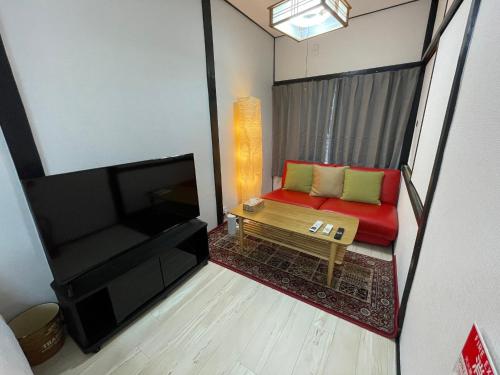 a living room with a red couch and a television at A&C House 新大阪 in Osaka