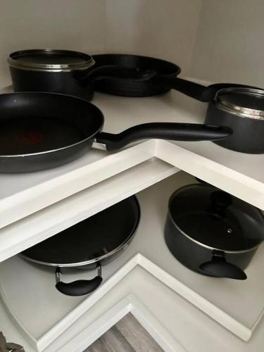 four black pots and pans on a white shelf at Valley Vibes and Beach Bliss Condo for Family Nomads in Waianae