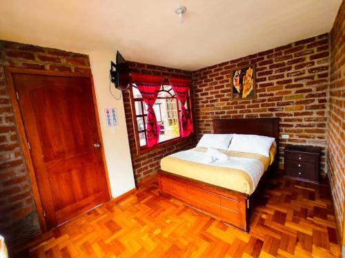 a bedroom with a bed and a brick wall at Hostal Viajero's in Baños